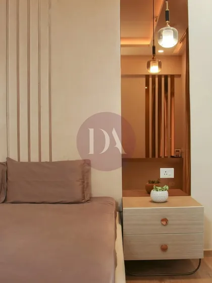 A close-up of a bedroom design focusing on texture and warmth. The fluted wall paneling behind the bed is complemented by a sleek wooden nightstand and a modern pendant light, creating a calm, contemporary feel.