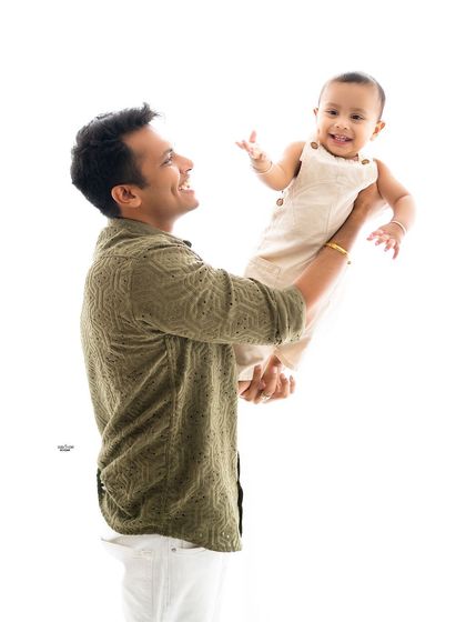 A father joyfully lifting his son in the air.