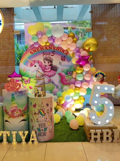 A colorful unicorn-themed fifth birthday. The setup includes a rainbow backdrop, a large unicorn foil balloon, and a 'TIYA' marquee.