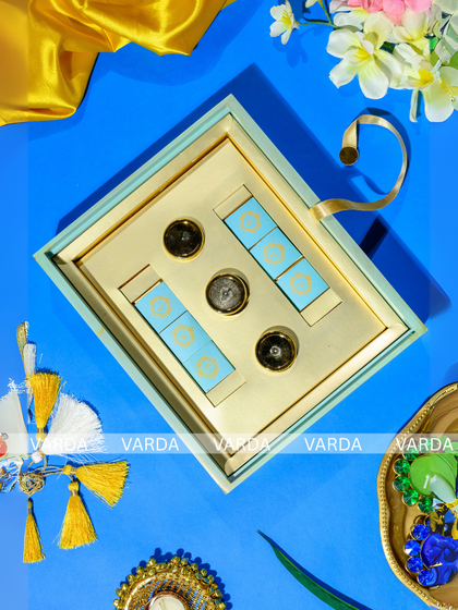 The interior of a luxury gift box, designed to hold both gourmet jars and small chocolates. The gold and light blue color scheme gives it a modern and sophisticated feel.