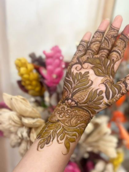 A close-up of a leafy, botanical design that covers the back of the hand and wrist.