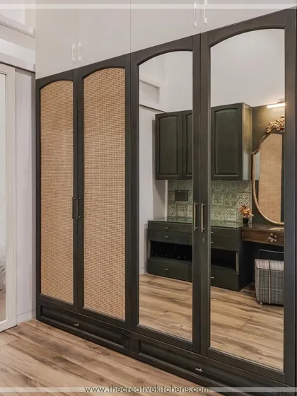 The reflection in the mirrored doors of this walk-in wardrobe showcases the meticulous design of the interior dressing space. The arched rattan and mirror panels add a classic, sophisticated touch to the solid wood PU shutters.