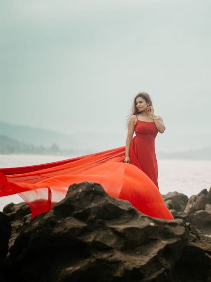 Making a statement against the rocks and sea. The vibrant red trail of this gown creates a powerful and dramatic image for any pre-wedding album.