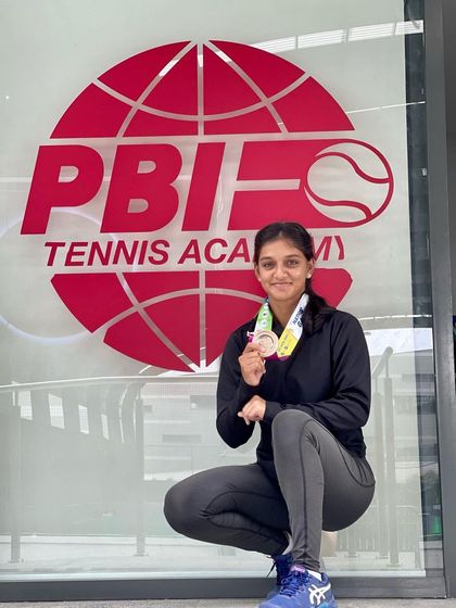 Soha Sadiq proudly displays her bronze medal from the National Games in Goa, pictured in front of the PBI Tennis Academy logo that represents her training home.