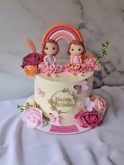 A beautiful cake for the first birthday of twin girls. I created custom figurines to match the special dresses they wore on their birthday, making it a truly personal keepsake.