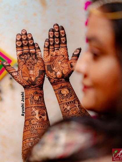 A candid shot of the bride admiring her henna, giving a sense of the scale and beauty of the full-arm design.