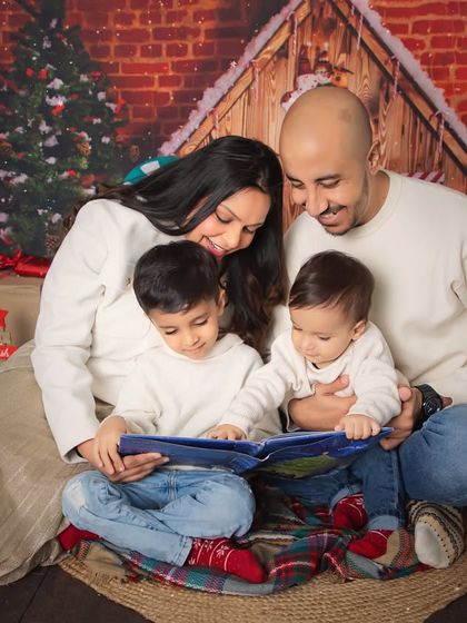 Story time by the Christmas tree. This cozy, festive family photo captures a sweet moment of togetherness during the holiday season.