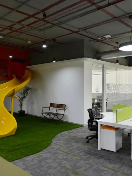 A fun yellow slide provides a playful alternative to the stairs in this award-winning office for Globant in Pune. The slide lands on a patch of green artificial turf.