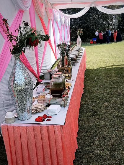 A beautiful outdoor party at a farmhouse, catered for 100 guests. The setup includes both the main buffet and a separate beverage and snack station.