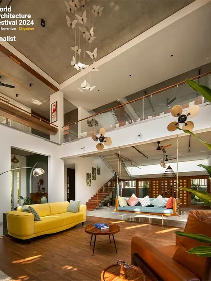 This view emphasizes the verticality of the space and the connection to the upper floor. The careful placement of furniture defines different functional zones within the open-plan layout.