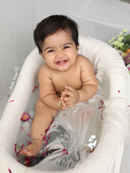 A joyful baby enjoys a playful "bath time" session with flower petals. These sessions are always a hit, resulting in the most genuine smiles.