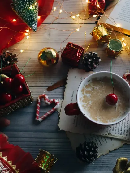 A festive Christmas-themed flat lay featuring a cup of hot chocolate, cherries, and holiday decorations for seasonal content.