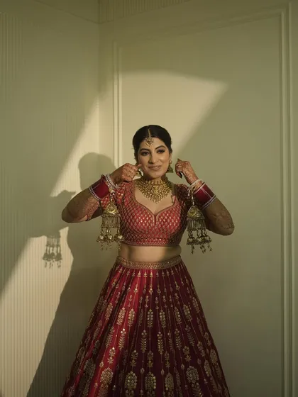 A candid moment of my sister getting ready. Her classic gold jewelry and red lehenga are quintessential bridal elements, and her makeup was designed to match that elegance.