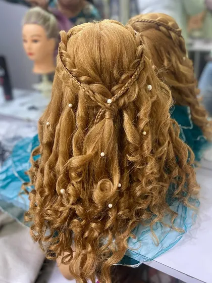 A full view of the braided crown and curly hairstyle created by a student. This showcases their skill in both braiding and styling.