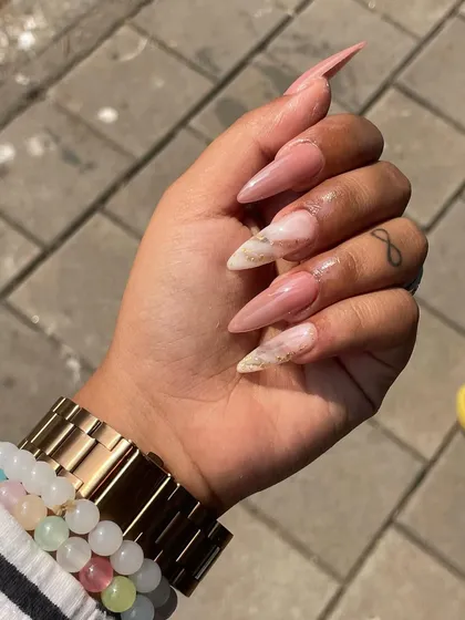 A close-up of this elegant marble nail art on long almond extensions. The soft blend of pinks and whites with a hint of gold creates a sophisticated look.