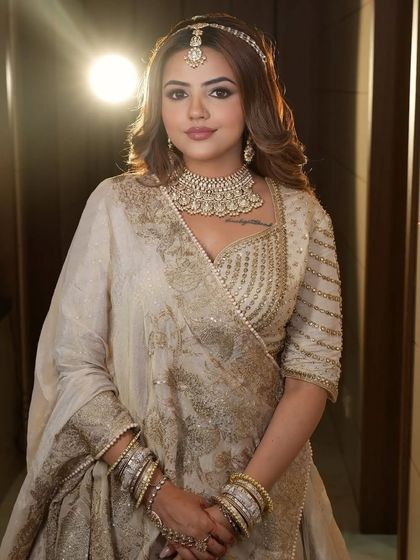 A confident pose in the ivory and gold lehenga, highlighting the detailed beadwork on the blouse and the heavy choker necklace.