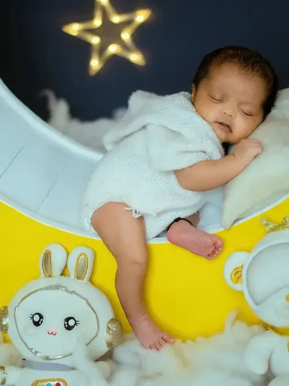 A peaceful newborn rests on the moon prop. I work patiently to capture these quiet moments when your baby is most relaxed.