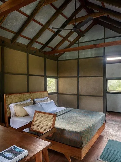 The interior of our earthen prefab studio showcases a simple, honest aesthetic. With exposed wooden beams, wattle and daub walls, and large windows framing the natural landscape, the space feels rustic yet refined, proving that sustainable living can be both beautiful and comfortable.
