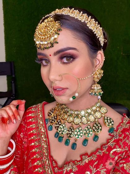 A close-up of this stunning bridal look. The combination of a red lehenga, green kundan jewelry, and dramatic eye makeup is pure perfection.