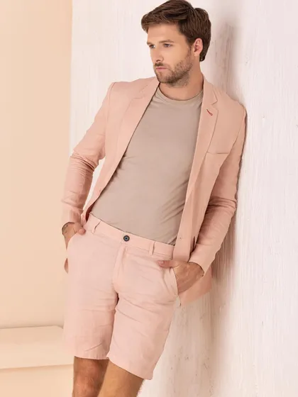 A smart-casual look from a men's linen campaign. A blush pink linen blazer is paired with matching shorts for a sophisticated yet relaxed summer outfit.