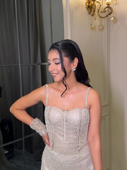 A candid moment showing off the complete look. The shimmery dress is complemented by a sophisticated and glamorous makeup style.