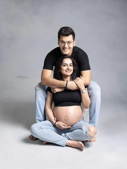 Love captured in its purest form. This casual, happy portrait in matching black tops and jeans shows a couple ready to welcome the newest member of their world.