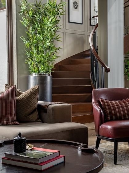 The House of Two Worlds in Gurugram is designed for balance, allowing two families to share one home while maintaining their individuality. This living area, with its warm tones and view of the helical staircase, is a shared space that feels both personal and connected.