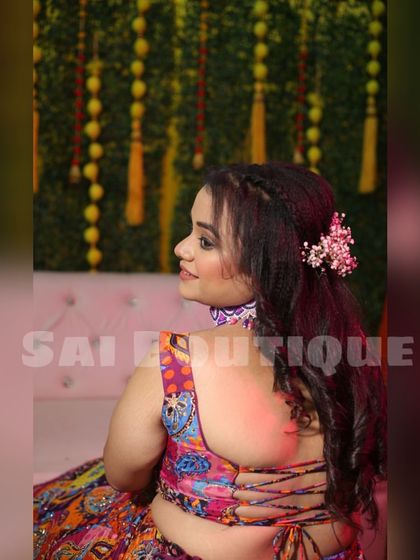 A close-up of the intricate back design of the bride's Mehndi lehenga. The criss-cross tie-up adds a modern and stylish touch.