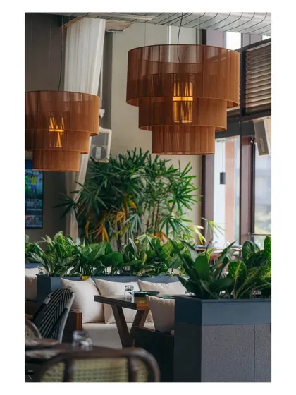 A close-up of the tiered wooden pendant lights, which cast a warm, diffused light. These fixtures add a sculptural element and enhance the cozy atmosphere of the lounge seating areas.