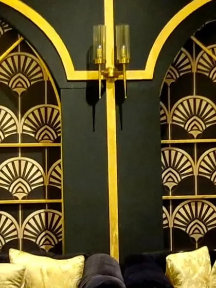 The finished Art Deco panels installed as window-like features, complete with elegant gold trim and wall sconces. This detail transformed a plain wall into a statement piece that reinforced the Great Gatsby-era theme.
