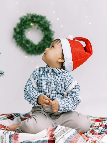 A little boy in a Santa hat, looking up in wonder. My portable studio setup allows us to create this magic right in your home.