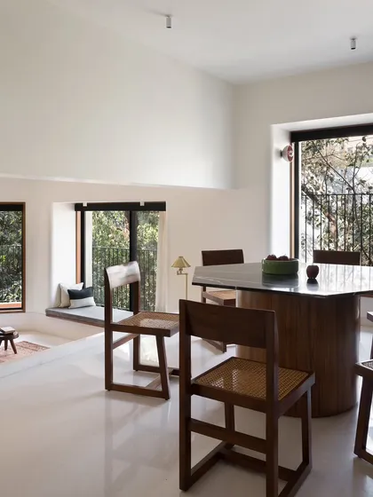 A hexagonal dining table I designed to create a unique focal point in this multi-level space. The solid, sculptural base is made of wood, while the top is a polished, dark stone, offering a durable and elegant surface.