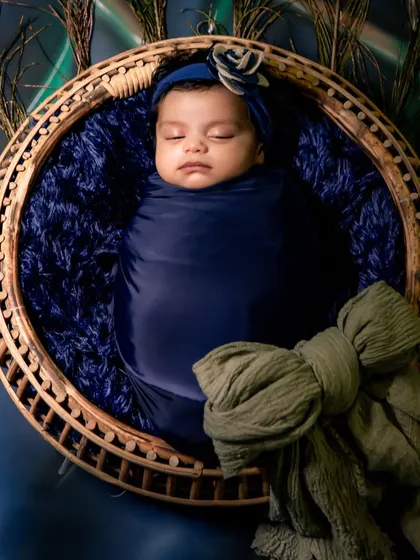 A peaceful newborn portrait. Using soft wraps and gentle posing, I create a safe and serene environment to capture the delicate features of your baby, framed by peacock feathers for a touch of artistry.