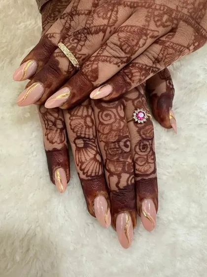 For brides who want a subtle look without sacrificing the glam. This design features soft peach pastel nails with elegant gold chrome detailing, which looks absolutely stunning next to the deep color of bridal henna.