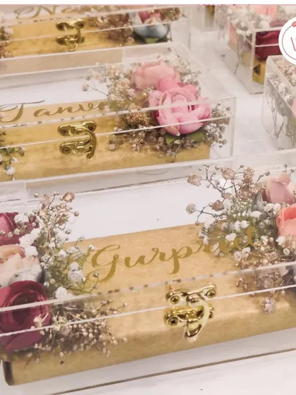 Exquisite coin packaging for wedding favors. These personalized acrylic boxes are adorned with dried flowers and custom names in gold.