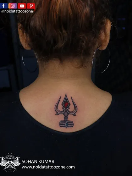A small but powerful Trishul tattoo on the back of the neck. The red gem detail adds a touch of color and focus to this symbol of Lord Shiva.