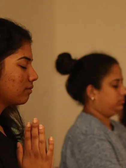 Two participants in a state of meditation, their hands in a gesture of prayer. Our sessions foster a sense of shared peace and community connection.