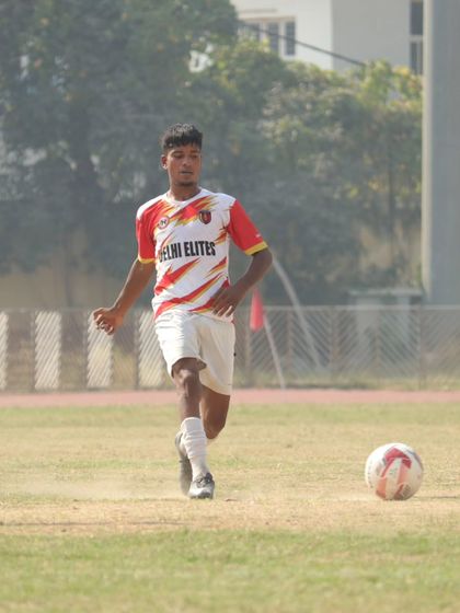 A player on the run, dribbling the ball with speed and purpose on the pitch during a match.