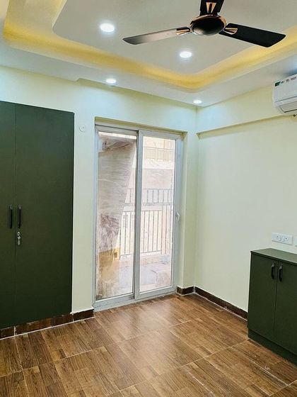 A simple and elegant bedroom setup with a matte-finish olive green wardrobe and a matching low-height storage cabinet.