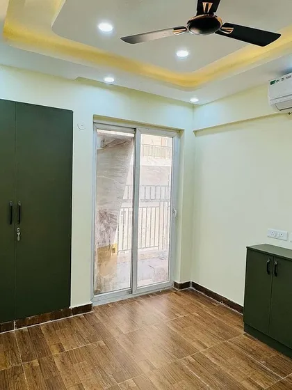 A simple and elegant bedroom setup with a matte-finish olive green wardrobe and a matching low-height storage cabinet.