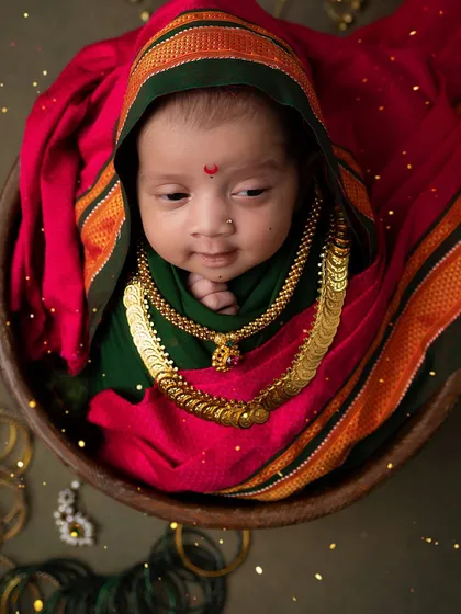 A sweet, sleepy expression. This newborn, adorned with traditional jewelry, is the picture of peaceful, festive bliss.
