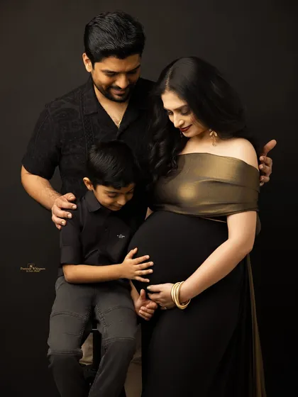 A modern family portrait that is both elegant and full of warmth. The son's gentle touch on his mother's baby bump adds a layer of beautiful storytelling to this glamorous shot.
