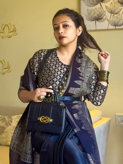 A detail shot focusing on the structured black bag and the rich textures of the brocade blouse and shawl. Every element is chosen to contribute to the overall opulent feel.