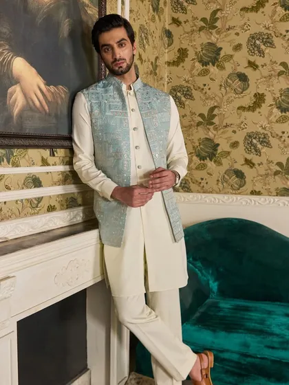 This versatile kurta set features an off-white kurta paired with a stunning powder blue jacket with geometric embroidery. It's perfect for a puja or a relaxed Sangeet evening.