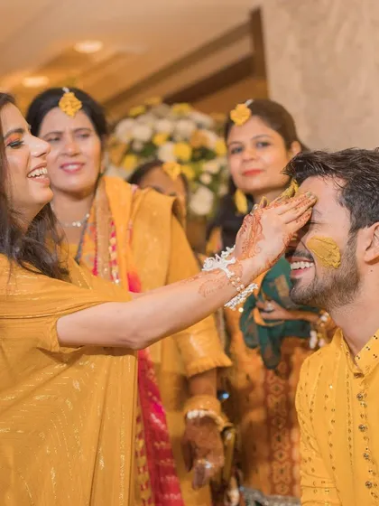 A gentler Haldi moment, with a guest applying turmeric to the groom's face.