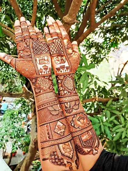 Full bridal mehendi that tells a story, incorporating traditional wedding symbols like palanquins and elephants, along with detailed patterns covering the hands and arms.