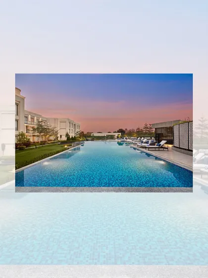 The expansive swimming pool at the Courtyard by Marriott, Gorakhpur, set against a beautiful sunset. The pool area is designed as a key recreational feature of this 7.5-acre lakeside property.