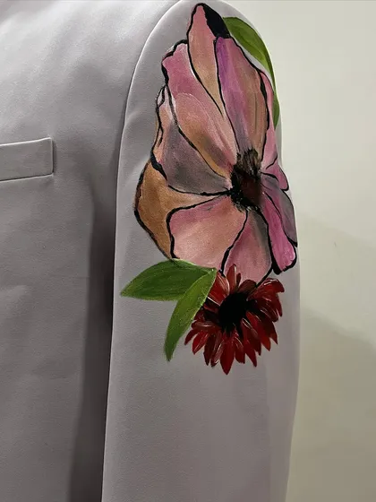 A detail of the floral artwork on the sleeve of a custom sherwani. Each flower is painted with distinct colors and shapes, contributing to the overall botanical composition.