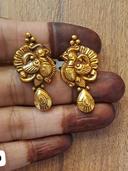 These peacock-themed earrings are crafted from 92.5 sterling silver with an antique gold plating. The teardrop-shaped drop completes the elegant design.