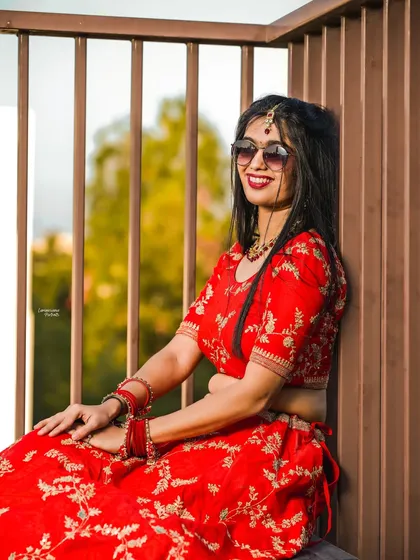 A close-up of the bride in her red lehenga and sunglasses, capturing her relaxed and happy expression in the warm sunlight.
